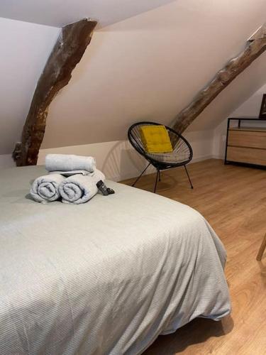 a bedroom with a bed and a chair with towels at Duplex le Brooklyn en Plein centre de Mordelles in Mordelles