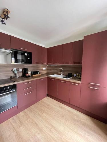 a large kitchen with red cabinets and a sink at Duplex le Brooklyn en Plein centre de Mordelles in Mordelles