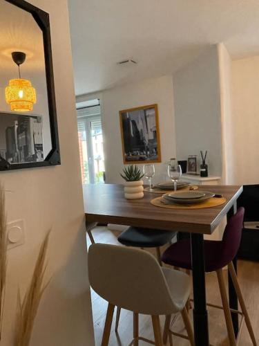 a dining room table with chairs and a table with wine glasses at Duplex le Brooklyn en Plein centre de Mordelles in Mordelles