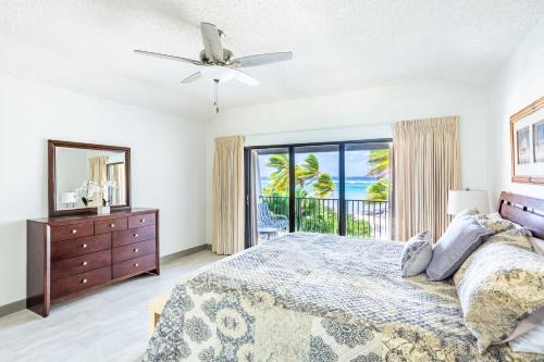 a bedroom with a bed and a dresser and a window at Beach Living at Villas Pappagallo BLDP in West Bay