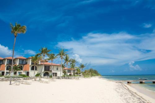 a row of houses on a beach with palm trees at Beach Living at Villas Pappagallo BLDP in West Bay