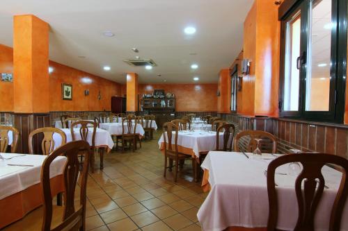 a restaurant with tables and chairs with white table cloth at Hotel Rural Hojaranzos in Tejeda de Tiétar