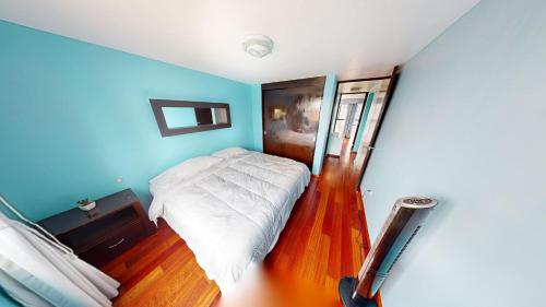 ein Schlafzimmer mit einem weißen Bett und blauen Wänden in der Unterkunft Bello departamento en Centro Histórico de la CDMX in Mexiko-Stadt