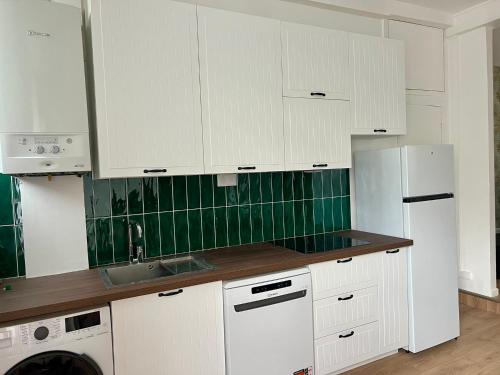 une cuisine avec des armoires blanches, un évier et un réfrigérateur dans l'établissement Appartement en duplex - M4 et RER B Arcueil-Cachan, à Bagneux