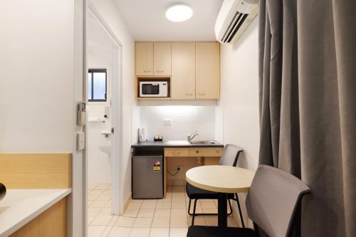 a small kitchen with a small table and a table and chairs at Asraport Motel in Brisbane