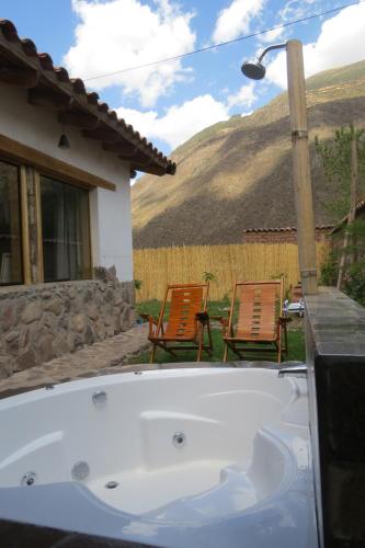 a bath tub in front of a house with two chairs at casa de campo-arin in Huaran