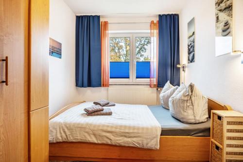 ein Schlafzimmer mit einem Bett mit blauen Vorhängen und einem Fenster in der Unterkunft Haus Frohsinn - Wohnung 3 in Binz