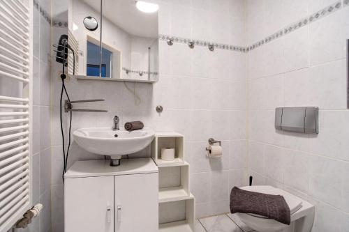 a white bathroom with a sink and a toilet at Bäckerhus - Ferienwohnung 5 in Wiek auf Rügen 