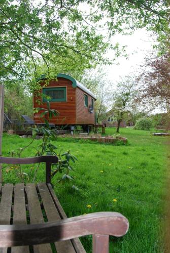 a house sitting in a field with a bench at Roulotte Ravel-Emoi Chambre Insolite de Charme in Ramillies