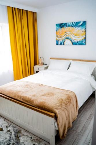 a bedroom with a white bed with a yellow curtain at TeCa apartament in Rădăuţi