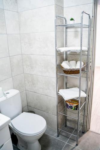 a bathroom with a toilet and a shelf with towels at TeCa apartament in Rădăuţi