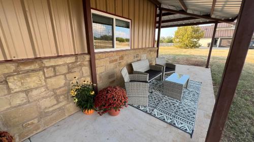 a porch with two chairs and a table and flowers at The Shophouse at Transplant Acres in Bandera