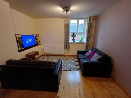 a living room with two black couches and a tv at Cental Retreat - 2 bedroom apartment in Belfast