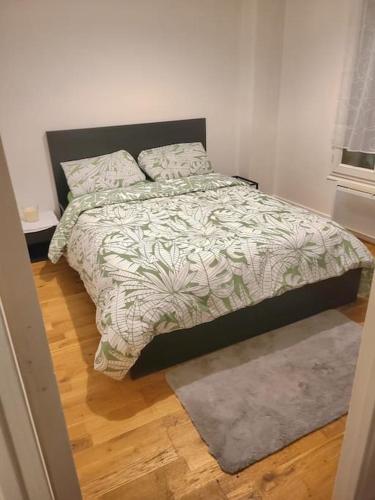 - une chambre avec un lit, une couette et un tapis dans l'établissement Nord de Paris pantin f2 terrasse, à Pantin