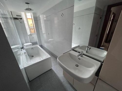 a white bathroom with a sink and a mirror at Odissea Apartment in Nettuno