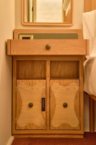 a wooden nightstand with a mirror and a bed at Now Now NoHo in New York