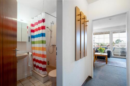 een badkamer met een regenboog douchegordijn en een toilet bij DKK7 Ferienwohnung Abendsonne F in Niendorf