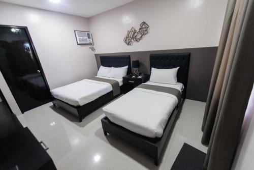 a small room with two beds and a chair at Bumble V Subic Hotel in Olongapo