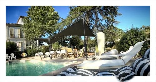 a swimming pool with chairs and an umbrella next to a pool at Mes nuits au château au domaine du pressoir in Pierrefeu-du-Var