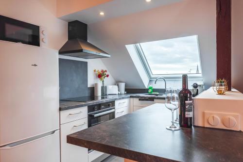 une cuisine avec un réfrigérateur blanc et un comptoir avec des verres à vin dans l'établissement Le Robin des Toits - Moderne, à Schiltigheim