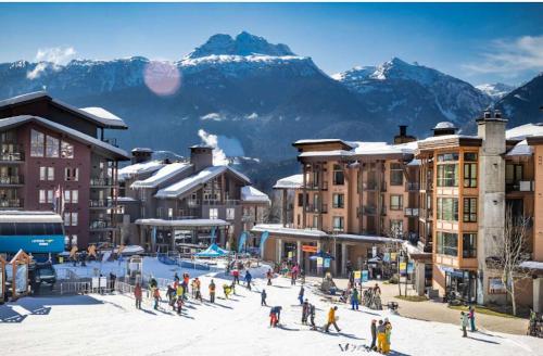 a group of people on skis in the snow near buildings at Revelstoke Alpine Retreat - RARE One-Bedroom Condo in Revelstoke