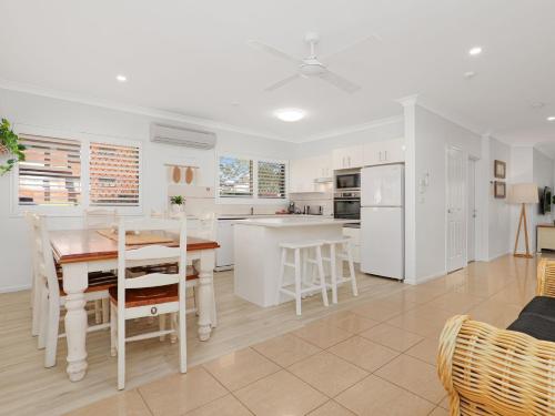 a kitchen with white appliances and a table and chairs at Martys Little Beach No 1 Two Story Apartment in Nelson Bay