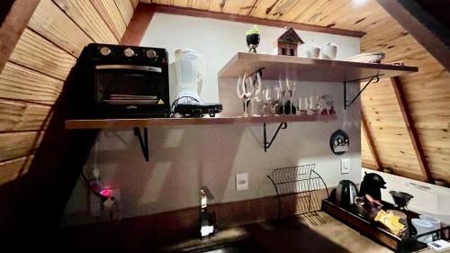 a kitchen with two shelves on the wall with dishes at Chalé de madeira com vista para o rio in Pomerode