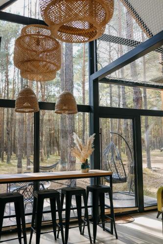 a dining room with a table and chairs and windows at Wyjątkowy domek w kompleksie Patyki Las Możliwości in Zelów