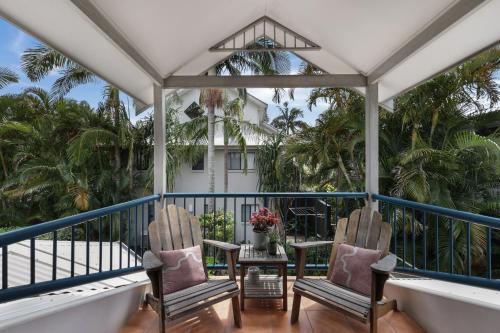 two chairs on a balcony with palm trees at Gosamara Apartments in Byron Bay