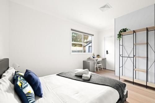 a white bedroom with a large bed and a desk at Elegant Queen Room at Botany - Nearby Airport - Shared Bathroom in Sydney