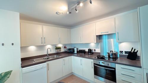 a kitchen with white cabinets and a sink at Shoreditch Britannia Apartments in London