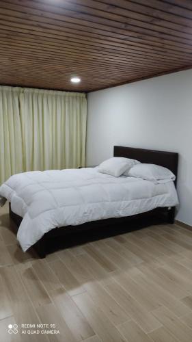 duże łóżko w sypialni z drewnianą podłogą w obiekcie Casa 10 w mieście Paipa