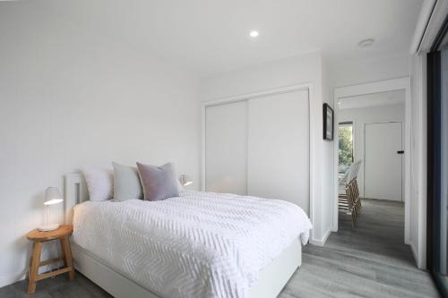 Dormitorio blanco con cama blanca y mesa en Three Pines - 300m to town, en Kiama