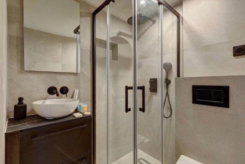 Un baño con ducha de cristal con lavabo. en Cosy room inside Batignolles - L60, en París