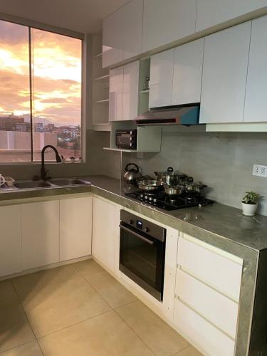 スクレにあるDepartamento en barrio Petroleroの白いキャビネットとコンロ付きオーブンを備えたキッチン