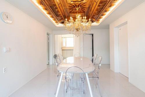 un comedor con una mesa blanca y una lámpara de araña en Gangneung station chandelier house 3b, en Gangneung