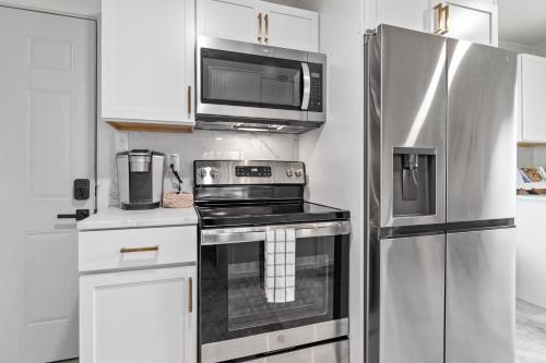 a kitchen with a stainless steel refrigerator and a microwave at Game Room and Huge Yard with Fire Pit Yard Games and BBQ Near UE and Downtown in Evansville