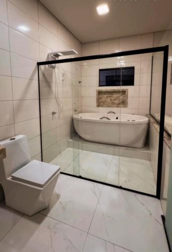 a bathroom with a bath tub and a toilet at Villa Mia in Teixeira de Freitas