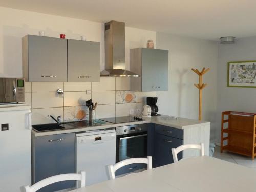 une cuisine avec des armoires blanches et un réfrigérateur blanc dans l'établissement Gîte calme avec terrasse près de Gérardmer - FR-1-589-158, à Le Tholy