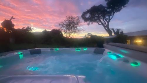 a hot tub in a backyard with a sunset in the background at Casa Marigold in Coyol