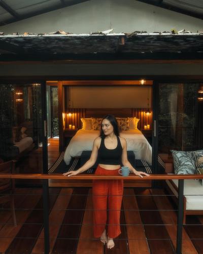 a woman sitting on a bench in front of a bed at Secret Bungalows Lechu in Chachagua