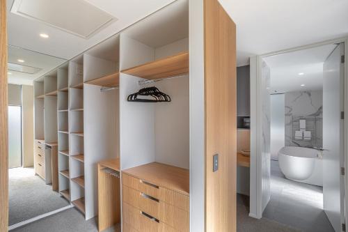 a bathroom with a walk in closet with a bath tub at Willow Waters - lakeside luxury - a Relax it's Done holiday home in Frankton Wharf