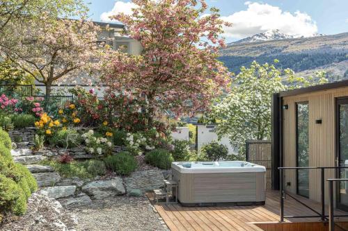 a hot tub sitting on a deck in a garden at Willow Waters - lakeside luxury - a Relax it's Done holiday home in Frankton Wharf