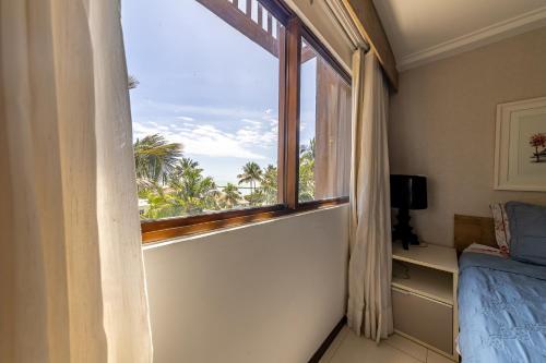 a bedroom with a window with a view of the ocean at Barra Bali Beach in Barra de São Miguel