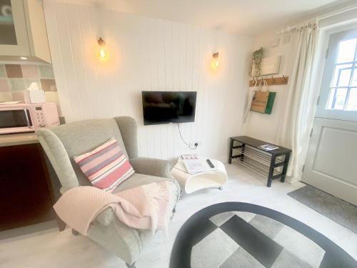 a living room with a couch and a tv at Stylish Cottage with Quay and River View in Lymington