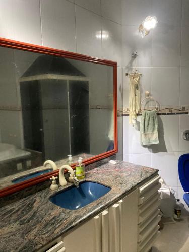 a bathroom with a sink and a mirror at Suíte privativa com cama Queen em casa ampla e confortável em casa compartilhada in Palhoça