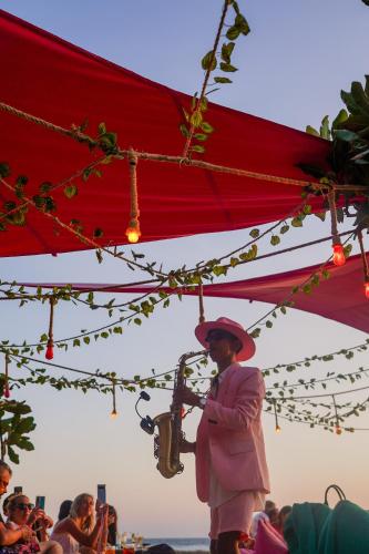 a woman playing a saxophone under a red umbrella at PinkCoco Gili Trawangan - Constant Surprises - for Cool Adults Only in Gili Trawangan