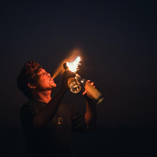 a man holding a torch and drinking a drink at PinkCoco Gili Trawangan - Constant Surprises - for Cool Adults Only in Gili Trawangan