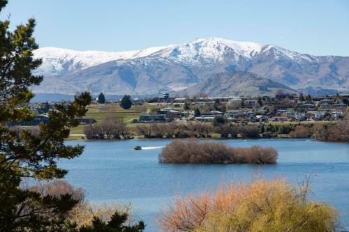 a lake with a town and snow covered mountains at Willow Waters - lakeside luxury - a Relax it's Done holiday home in Frankton Wharf