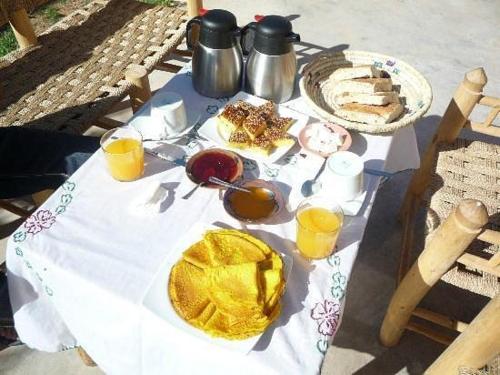 a table with food and two cups of orange juice at kasbah De Alami hdida commune de ait ouassif kelaa mgouna tinghir in Kalaat MGouna